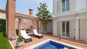 A pool area with lounge chairs, a barbecue setup, and a small garden. - Elegant Villa Rafaelle with pool (Vabriga)