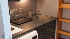 Een kleine keuken met een ingebouwde wasmachine, een magnetron en een spoelbak.