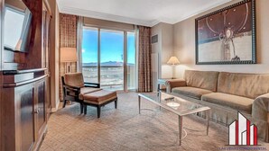 A spacious living room with a large window offering a city view, a sofa, a coffee table, and a television.