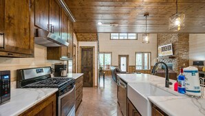 A kitchen with wooden cabinets, a stove, and a large island with a sink.