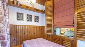 A cozy room with wooden paneling, a bed with a checkered bedspread, a shelf with books, and a wall with framed signs.