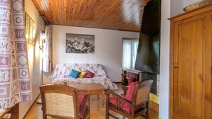 A cozy room with a wooden ceiling, a bed with patterned bedding, a fireplace, and a large wooden cabinet.