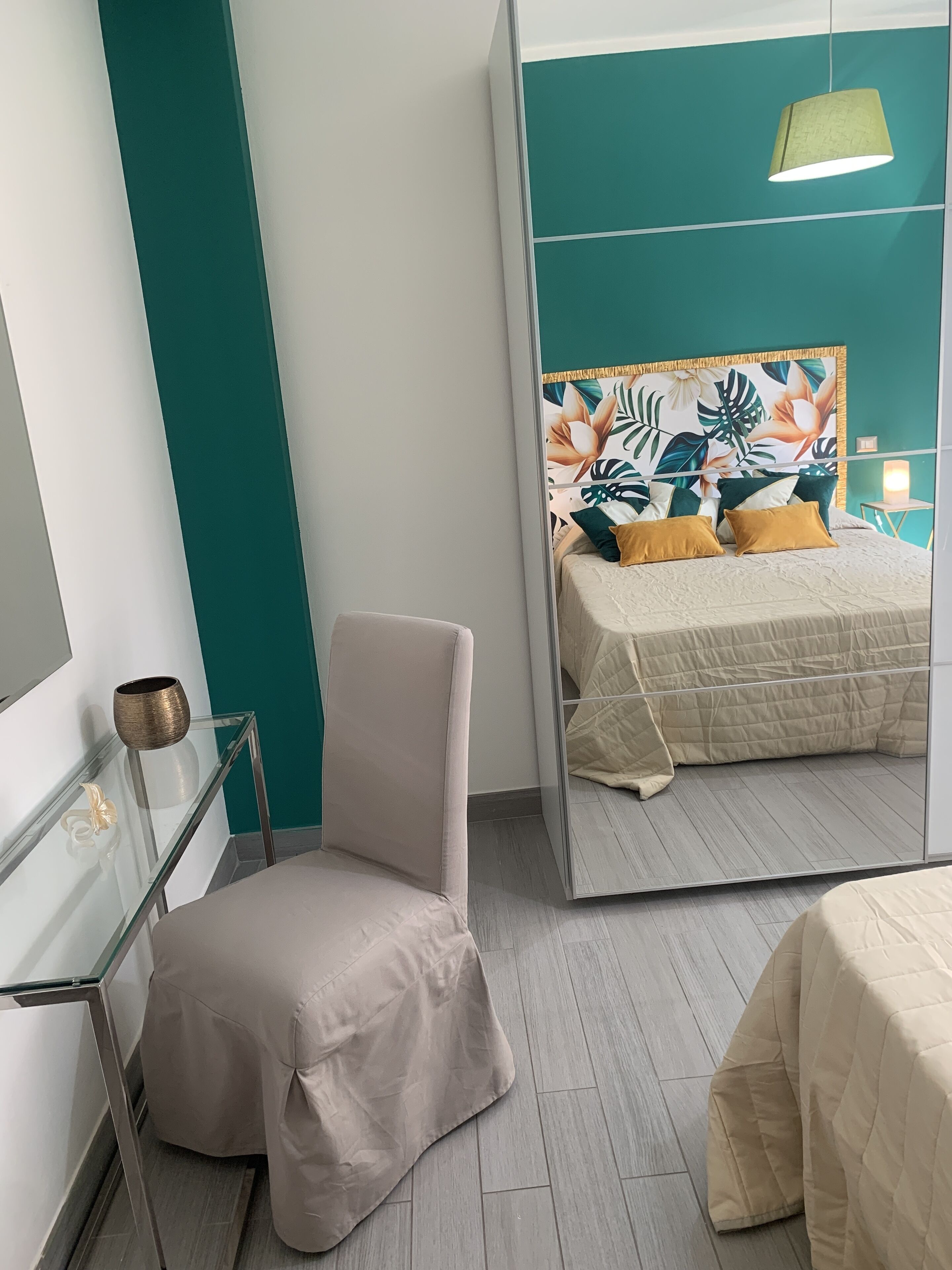 Een moderne slaapkamer met een bed, een stoel, een spiegel en een nachtkastje.