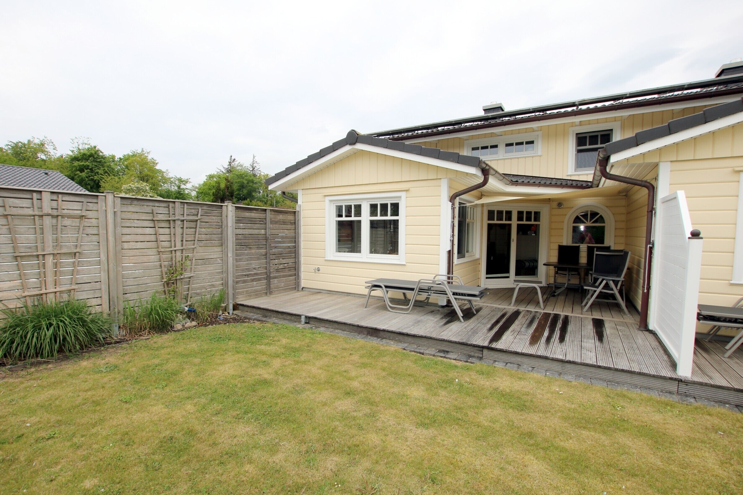 A house with a covered patio, a fenced yard, and a wooden deck.