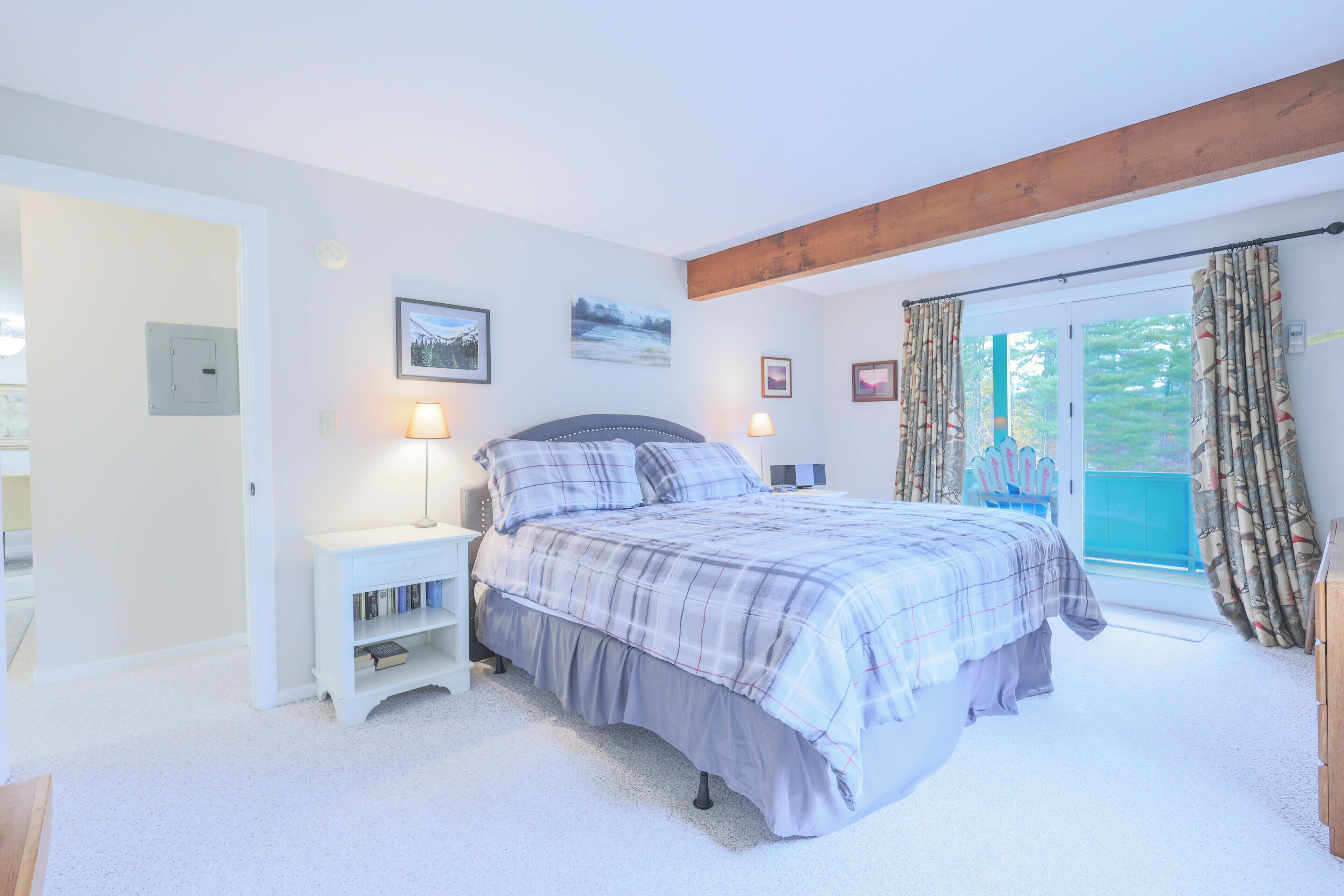 A bedroom with a bed, bedside tables, a bookshelf, and a window with curtains.