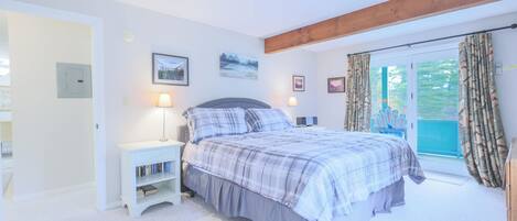 A bedroom with a bed, bedside tables, a bookshelf, and a window with curtains.