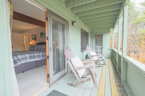 A room with a bed, a sliding glass door, a rocking chair, and a view of trees. - Official Seasons RMC Condo 11D - 2 Bedroom  - sleeps 6 - Dog Fees (Bartlett)