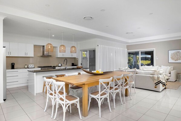 A modern kitchen with white cabinetry, a wooden dining table, and white chairs.