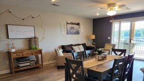A dining area with a wooden table and chairs, a sofa, and a desk with drawers and decorative items. - Walk-in Condo! Enjoy The Lake Life, 3B/2B Sleeps 9, 2 Pools, Boat Slip & Beach!  (Osage Beach)