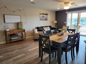 A dining area with a wooden table and chairs, a sofa, and a desk with drawers and decorative items.