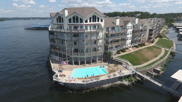 A multi-story hotel with a pool on the ground level, surrounded by water. - Walk-in Condo! Enjoy The Lake Life, 3B/2B Sleeps 9, 2 Pools, Boat Slip & Beach!  (Osage Beach)