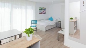 A modern bedroom with a bed, a desk, a chair, and a potted plant. - Spreepolis Boardinghouse (Berlin-Oberschöneweide)