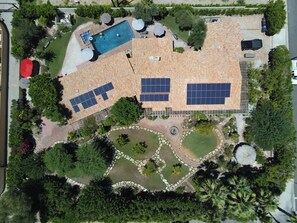 An aerial view of a residential property with a swimming pool, solar panels, and a landscaped garden.