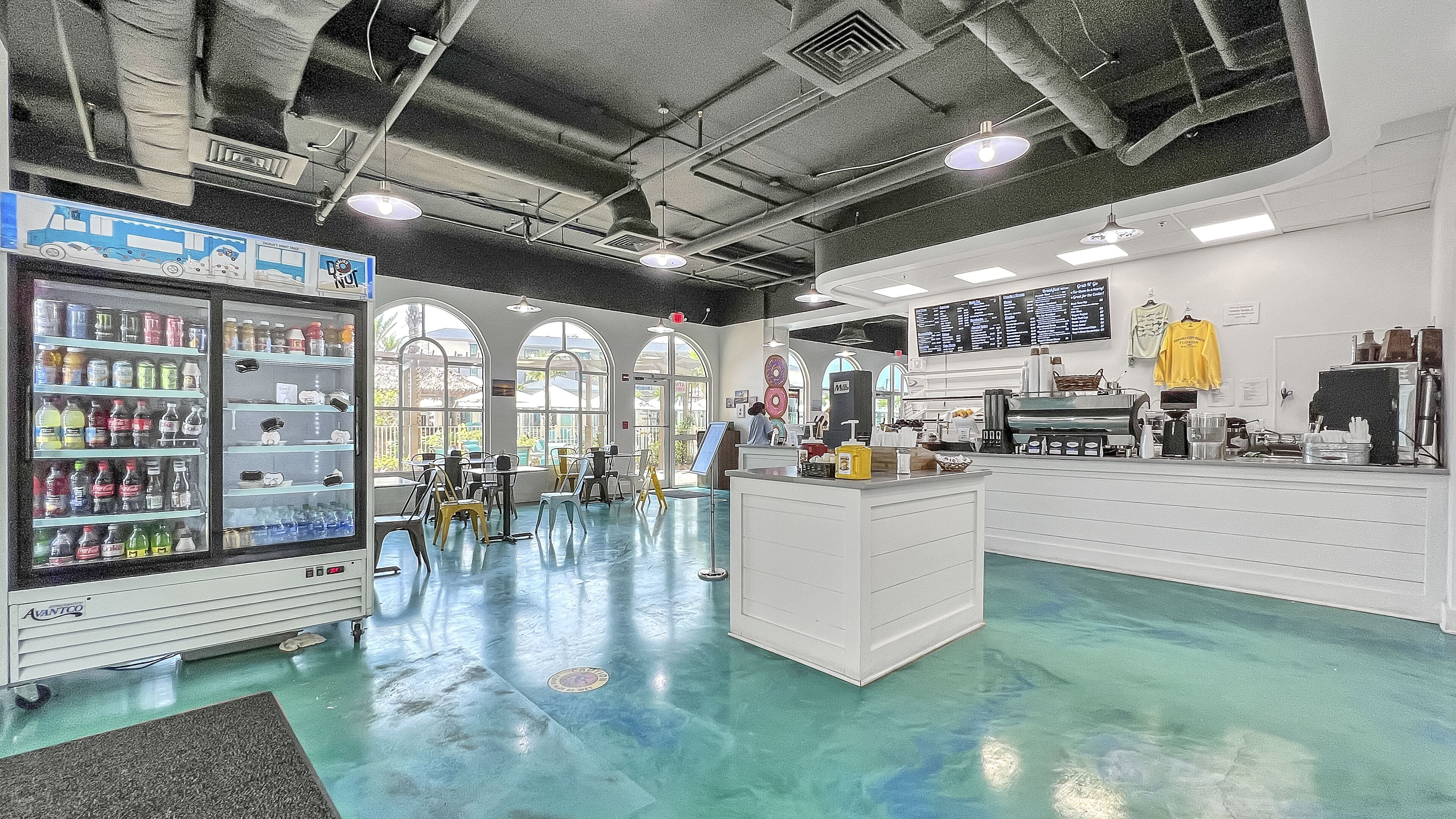 A spacious indoor area with a vending machine, a coffee station, and a seating area with tables and chairs.