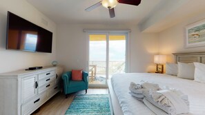 A hotel room with a bed, a TV, a desk, a chair, and a balcony with a view.