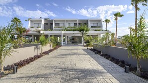 Un hotel moderno con un patio central, varios pisos y una fachada simétrica.
