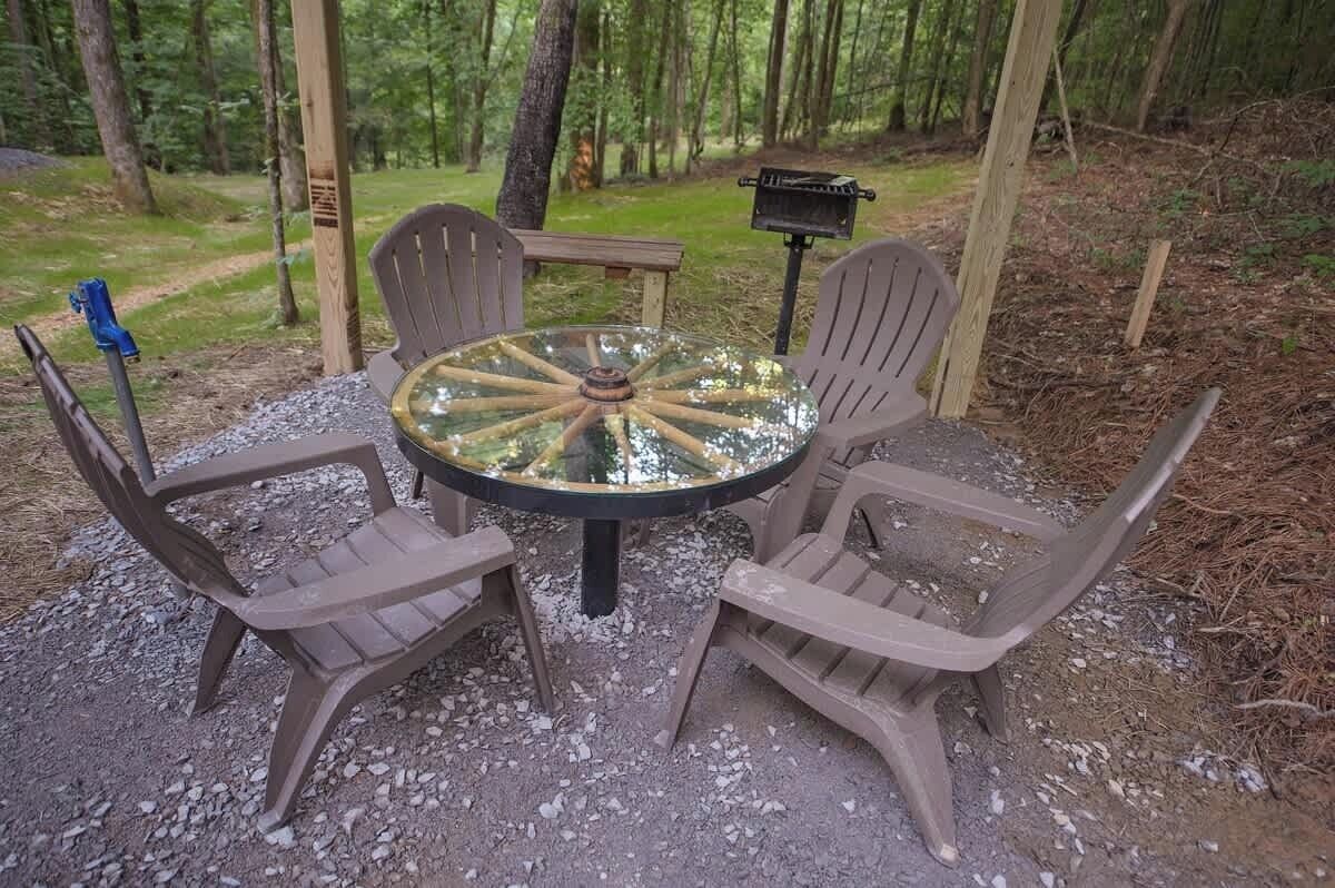 Una mesa redonda con cubierta de vidrio y cuatro sillas alrededor.