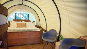 Une pièce aménagée avec une tente, un lit, une chaise et une petite table.