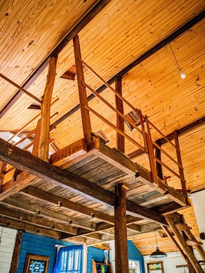 A high ceiling with exposed wooden beams and a ladder.