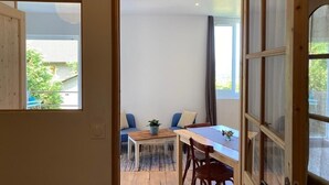 Una habitación con una mesa y sillas de madera, un sofá y una ventana con cortinas.