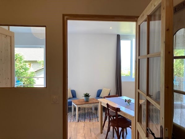 A room with a wooden table and chairs, a sofa, and a window with curtains.