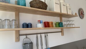 Una repisa de cocina con varios recipientes, incluyendo frascos etiquetados 'FARINE' y 'PÂTES', una botella azul y una cesta.