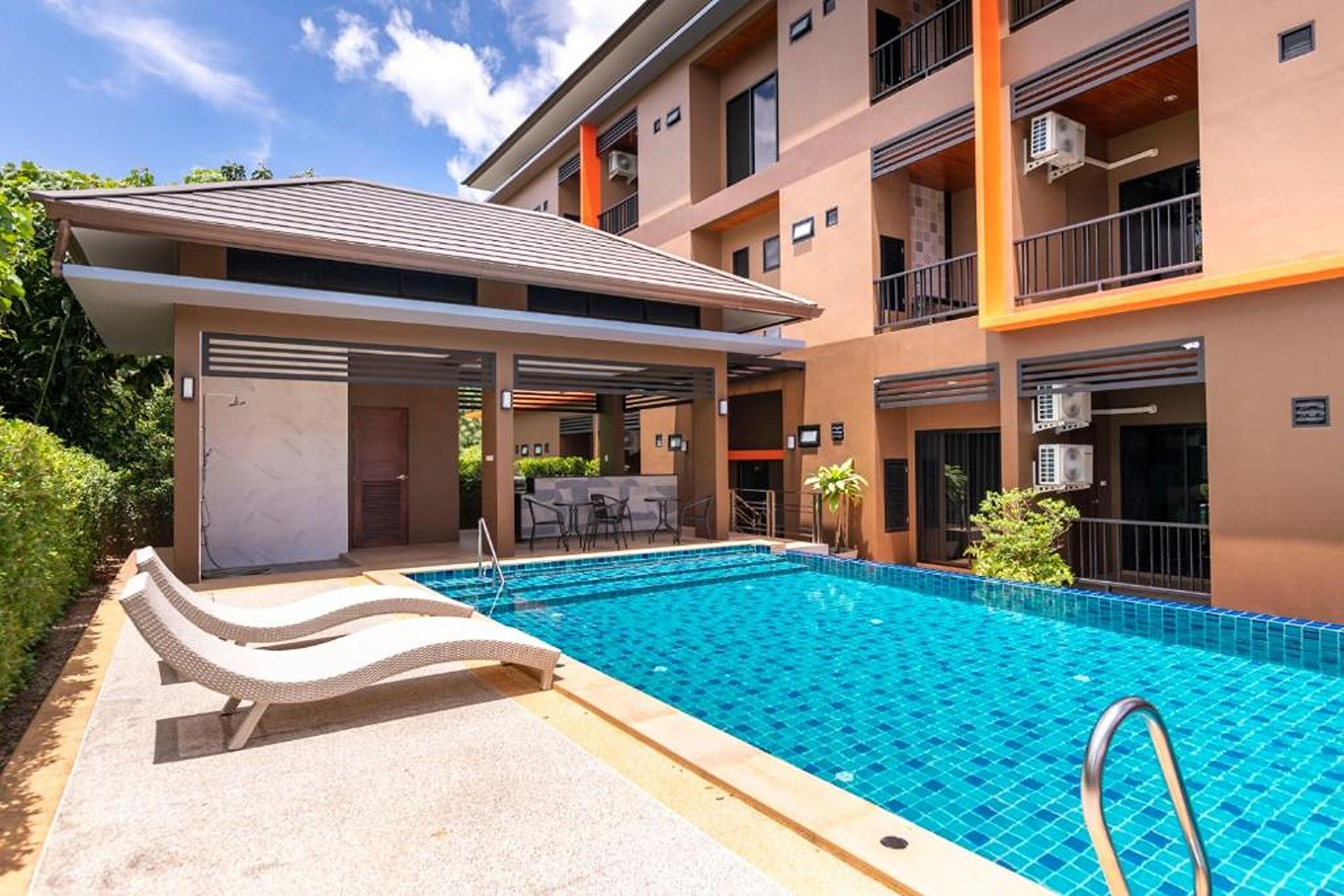 Un edificio moderno con piscina, mobiliario exterior y balcones.