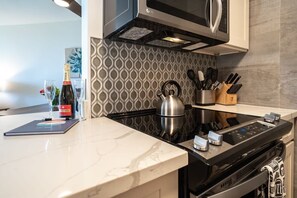 Una cocina moderna equipada con microondas, hervidor y cocina vitrocerámica digital.