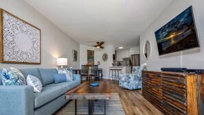 A living room with a sofa, coffee table, and a TV on a wooden cabinet. - Modern and Relaxing Oceanfront Vistas (Kihei)