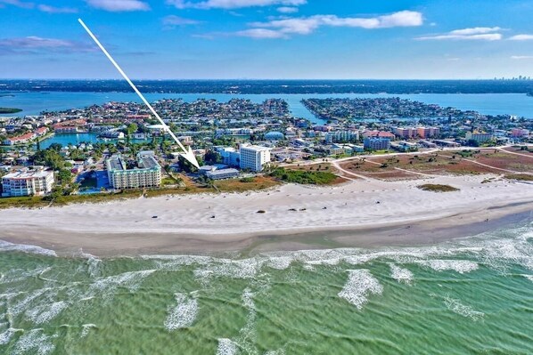 An aerial view of a coastal city with a beach, hotels, and a marina.
