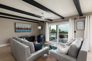 A living room with a sofa, a coffee table, a blue armchair, and a ceiling fan.