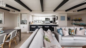 A modern living room with a sofa, dining table, and kitchen in the background.