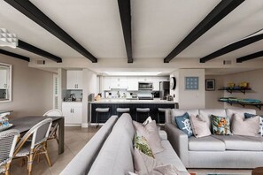 A modern living room with a sofa, dining table, and kitchen in the background.