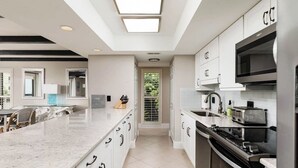 A modern kitchen with white cabinetry, a central island, a built-in oven, and a microwave.
