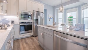 A modern kitchen with stainless steel appliances, white cabinetry, and a large window providing natural light. - 6 Seat Golf Cart ~ Sleeps 9 ~ Arcade Games (Santa Rosa Beach)
