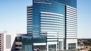 Un bâtiment moderne à plusieurs étages, doté d’une façade incurvée en verre, portant l’inscription « Université du Texas, centre MD Anderson de lutte contre le cancer ».