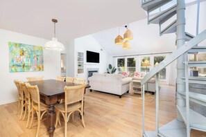 Un intérieur moderne comprenant un coin repas, un canapé, un escalier et de grandes fenêtres.