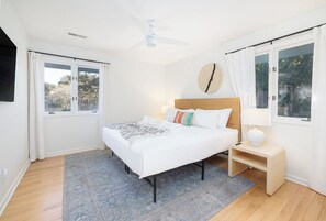 A bedroom with a bed, bedside table, lamp, and a ceiling fan. - Tropicana Cabana with Fenced Yard (Isle Of Palms)