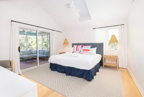 Un dormitorio con cama, puerta corrediza de vidrio hacia un balcón y ventana con vistas.