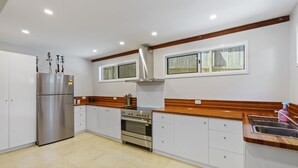 A modern kitchen with a stainless steel refrigerator, built-in oven, and wooden countertop. - Beautiful ground floor unit in Central Point Lookout (Point Lookout)