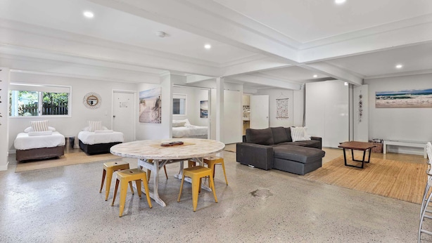 A spacious living area with a round table, yellow stools, a grey sofa, and a small wooden table. - Beautiful ground floor unit in Central Point Lookout (Point Lookout)
