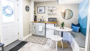 A compact kitchen with a microwave, sink, and a small dining area with a chair and table.