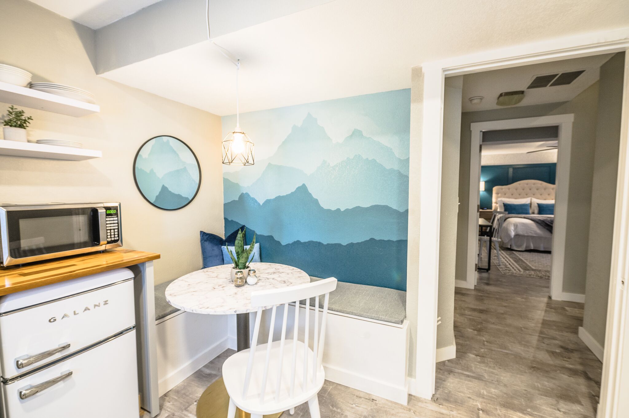 A modern kitchen with a microwave, a sink, and a dining area with a table and chairs.