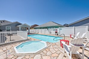 Un jardin avec une piscine, un jacuzzi et un espace salon extérieur.