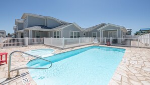 Une maison d’habitation dotée d’une piscine, d’une clôture en bois peinte en blanc et d’une terrasse en pierre.