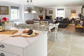 A spacious living area with a stone fireplace, a dining table set with food, and a comfortable seating arrangement. - Luxury Scottish farmhouse (Perth)