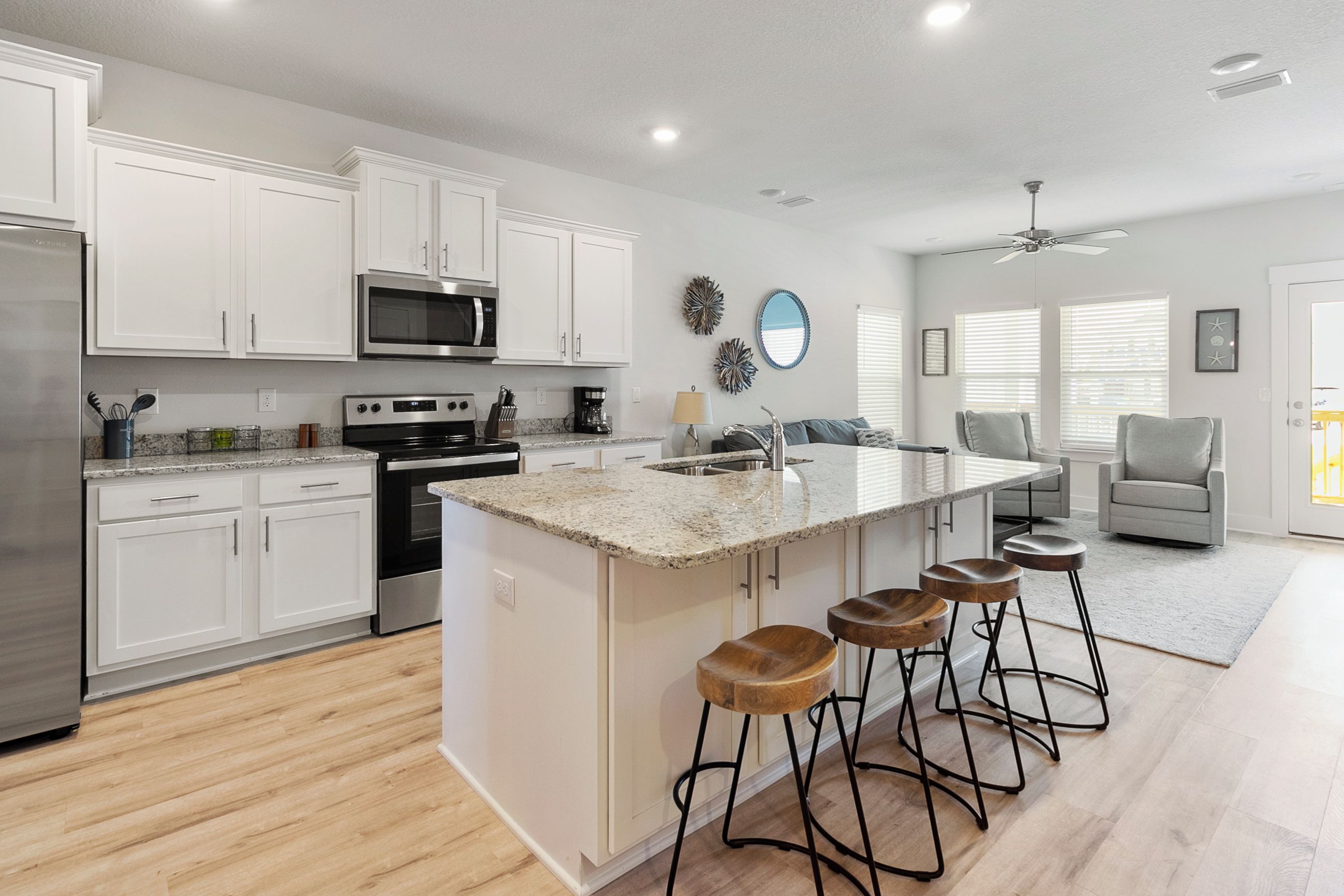 A modern kitchen with white cabinets, a granite countertop, and a central island with stools.