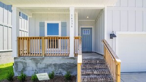 A two-story residential building with a covered porch, a staircase, and a garage. - Bring The Whole Family And Friends, Too! White Beaches Are Waiting! (Perdido Key)