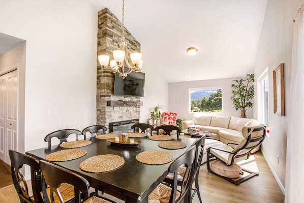 A dining area with a stone wall, a chandelier, and a view of the outdoors.