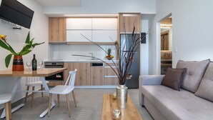 A modern kitchen with wooden cabinets, a dining area with white chairs, and a living room with a sofa. - Secretnest 17 apartment near the beach, Plakias (Plakias)